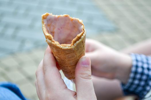 Ice cream cone in hand pastel gray background. . Concept of eating ice cream. A man holds a waffle without ice cream in his hand on a different light background. High quality photo