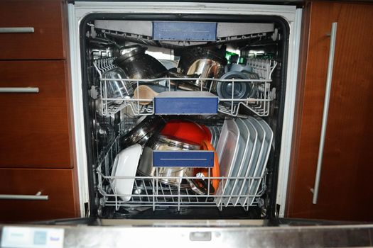 Transparent and black and white dishes as well as cutlery and glasses are washed in the dishwasher, inside view, drops and splashes of water. High quality photo