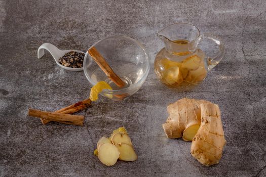 preparation of a ginger and cinnamon infusion with fresh produce natural roots and cinnamon stick served in a pitcher and a cup