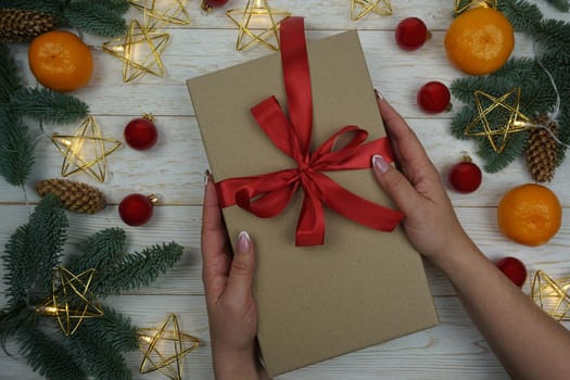 In women's hands, a gift in craft paper with a red bow. High quality photo