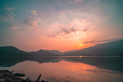 Panorama scenic of mountain lake with perfect reflection at sunrise. beautiful mountain range landscape with pink pastel sky with hills on background and reflected in water. Nature lake landscape