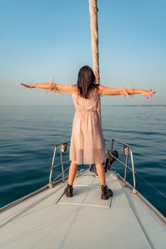 Woman standing on the nose of the yacht at a sunny summer day, breeze developing hair, beautiful sea on background.