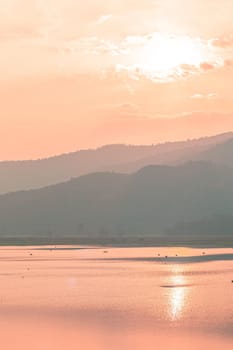 Panorama scenic of mountain lake with perfect reflection at sunrise. beautiful mountain range landscape with pink pastel sky with hills on background and reflected in water. Nature lake landscape