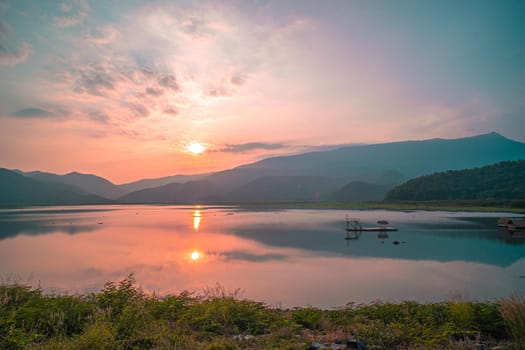 Panorama scenic of mountain lake with perfect reflection at sunrise. beautiful mountain range landscape with pink pastel sky with hills on background and reflected in water. Nature lake landscape