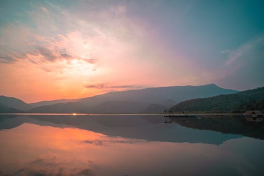 Panorama scenic of mountain lake with perfect reflection at sunrise. beautiful mountain range landscape with pink pastel sky with hills on background and reflected in water. Nature lake landscape