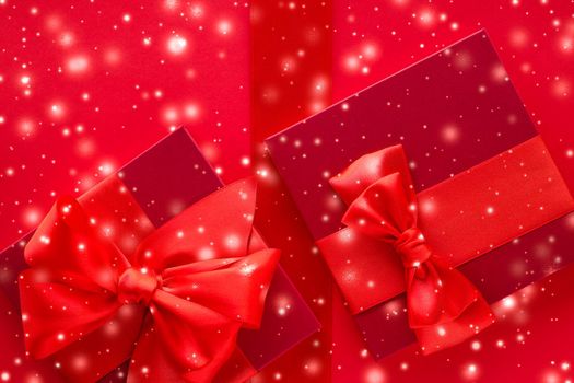 New Years Eve celebration, wrapped luxury boxes and Valentines Day card concept - Winter holiday gifts and glowing snow on red background, Christmas presents surprise