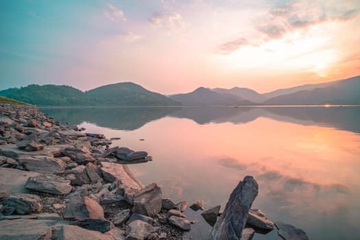 Panorama scenic of mountain lake with perfect reflection at sunrise. beautiful mountain range landscape with pink pastel sky with hills on background and reflected in water. Nature lake landscape