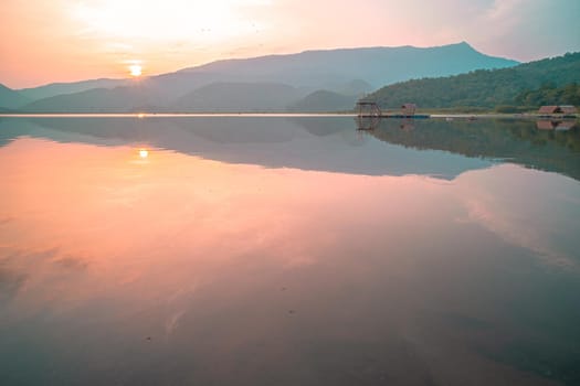 Panorama scenic of mountain lake with perfect reflection at sunrise. beautiful mountain range landscape with pink pastel sky with hills on background and reflected in water. Nature lake landscape
