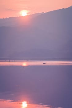 Panorama scenic of mountain lake with perfect reflection at sunrise. beautiful mountain range landscape with pink pastel sky with hills on background and reflected in water. Nature lake landscape