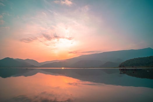 Panorama scenic of mountain lake with perfect reflection at sunrise. beautiful mountain range landscape with pink pastel sky with hills on background and reflected in water. Nature lake landscape
