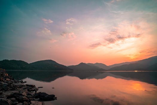 Panorama scenic of mountain lake with perfect reflection at sunrise. beautiful mountain range landscape with pink pastel sky with hills on background and reflected in water. Nature lake landscape