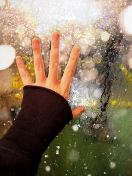 hand of young woman at the window in the rain