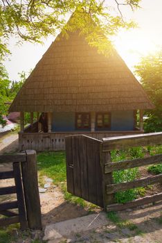 A typical Ukrainian landscape in spring or summer: white clay hut with a straw roof and a tree in the foreground.