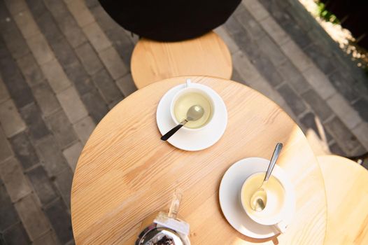 View from above of teacups with healthy antioxidant herbal drink on a round wooden table. Copy space. Food and drink consumerism