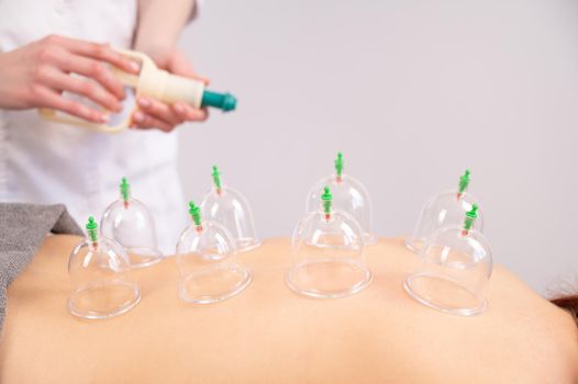 Female massage therapist uses vacuum cans on the patient's back