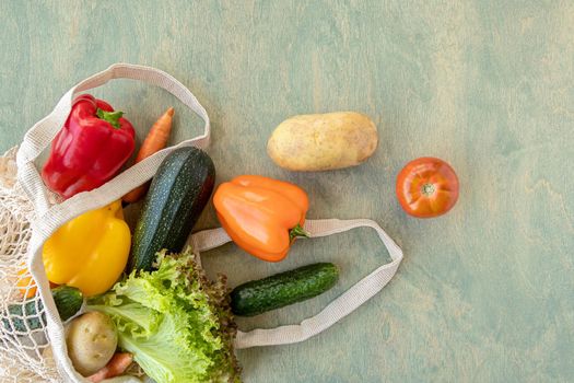 fresh vegetables in an eco bag on a wooden background. bell pepper, zucchini, lettuce, potato, tomato in a reusable bag. the concept of eco and respect for nature. copy space