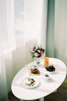 Bride breakfast stands on a served white table by the window. High quality photo