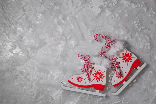 figurines of ice skates with a red pattern on frosty ice, sparkling frost or water crystals. winter sport or entertainment concept. copy space