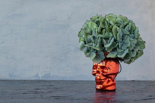 vase in the form of a skull with hydrangea instead of hair. background for halloween. copy space