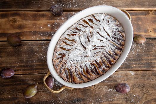 ready plum cake sprinkled with powdered sugar on a wooden table sweet seasonal dessert, High quality photo