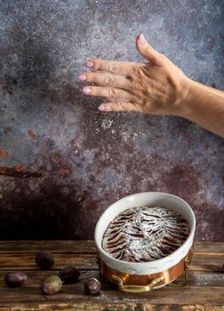 woman sprinkled with powdered sugar plum cake, baking homemade sweet dessert. High quality photo