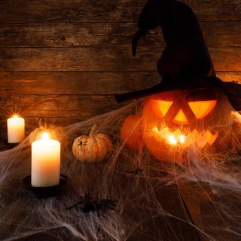 Festive mystical halloween interior. Pumpkin, spider web, burning candles, spiders on dark wooden background