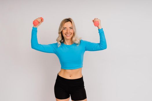 Sporty girl doing exercise with dumbbells, silhouette studio shot over a dark and white background