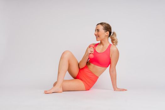 Full length portrait of smiling young woman in a sportswear isolated over studio background.