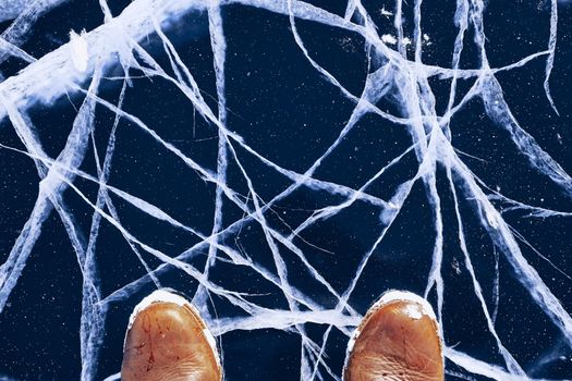 Human feet in boots on the ice lake Baikal. blue lake ice.