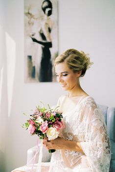 Bride with a bouquet of flowers sits in a chair. High quality photo