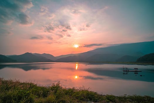 Panorama scenic of mountain lake with perfect reflection at sunrise. beautiful mountain range landscape with pink pastel sky with hills on background and reflected in water. Nature lake landscape