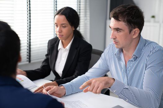 Competent office workers from various nationalities are debating, discussing and brainstorming in the meeting room. A group of employees is collaborating to achieve their business objectives.