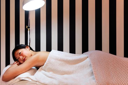 young woman relaxes lying on the couch before a relaxing massage in the beauty salon, concept of body care and wellness