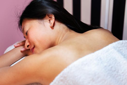 beautiful asian woman relaxes lying on the couch after a relaxing massage in the beauty salon, concept of body care and wellness