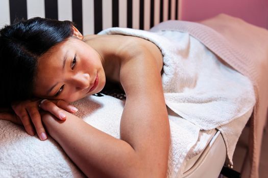 beautiful young woman relaxes lying on the couch before a relaxing massage in the beauty salon, concept of body care and wellness