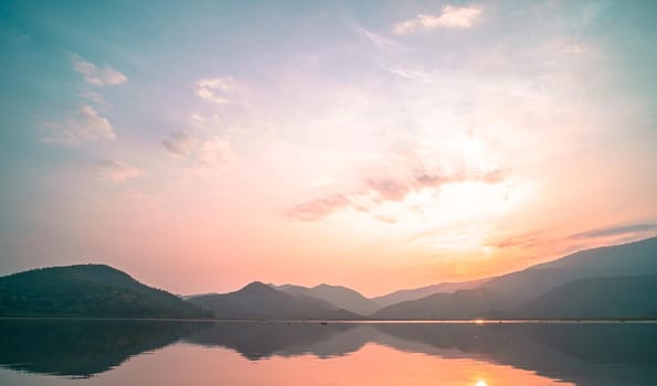 Panorama scenic of mountain lake with perfect reflection at sunrise. beautiful mountain range landscape with pink pastel sky with hills on background and reflected in water. Nature lake landscape