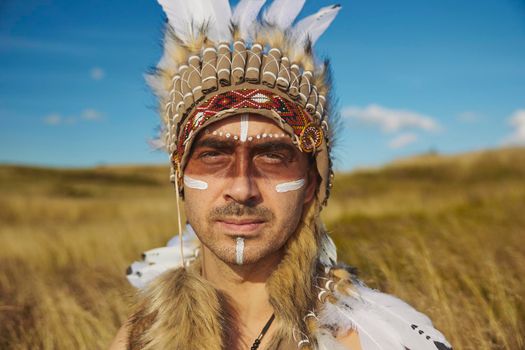 A man in traditional Native American clothing in the steppe.