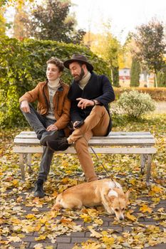 Father and son with a pet on a walk in the autumn park.