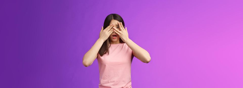 Shocked concerned asian girl witness terrible crime feel insecure scared, close eyes frightened shook, open mouth, gasping upset, standing stupor drop jaw, pose purple background. Copy space