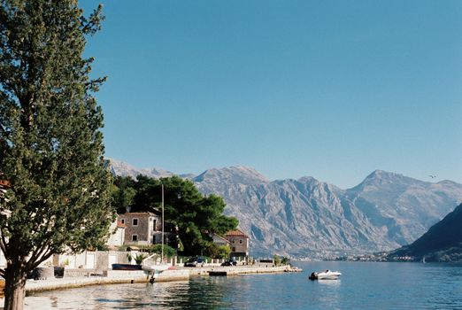 Stone houses on the shore of the bay against the backdrop of mountains. Montenegro. High quality photo