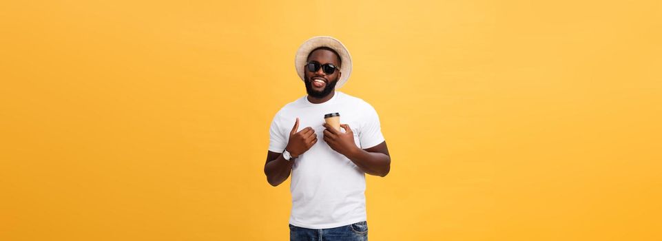 Stylish young african american man holding cup of take away coffee isolated over yellow background