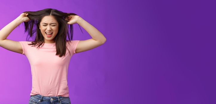 Upset distressed asian brunette girl frowning screaming, pull out hair fed up poor haircare, disappointment weak strands, stand purple background annoyed, pissed complain hairsalon.