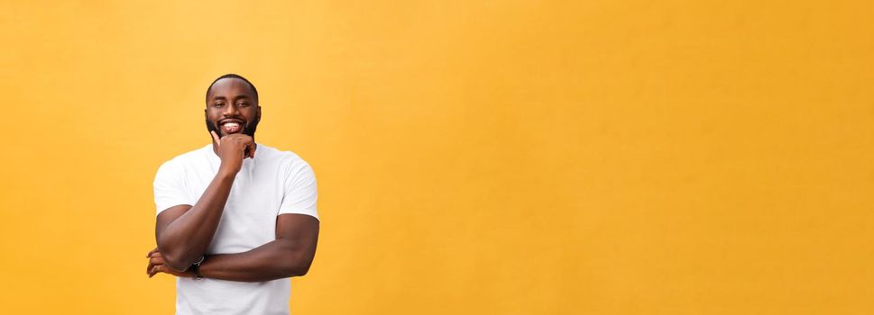 Portrait of a modern young black man smiling with arms crossed on isolated yellow background.