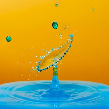Fresh blue Water drop with droplet and rings on the yellow background