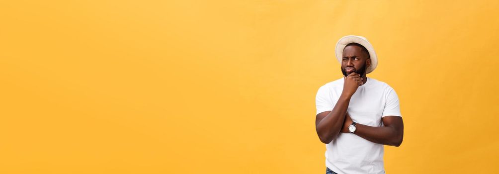 Human face expressions, emotions and feelings. Handsome young African American man looking up with thoughtful and skeptical expression, holding finger on his chin, trying to remember something