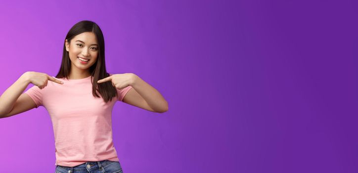 Active energized friendly tender asian stylish girl introduce herself, pointing chest proudly, smiling boastful, describe own achievements, bragging accomplishments, stand pleased purple background.