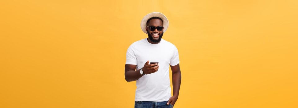 Cheerful African American man in white shirt using mobile phone application. happy dark skinned hipster guy read news from social network in mobile phone