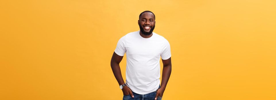 Portrait of delighted African American male with positive smile, white perfect teeth, looks happily at camera, being successful enterpreneur, wears white t shirt