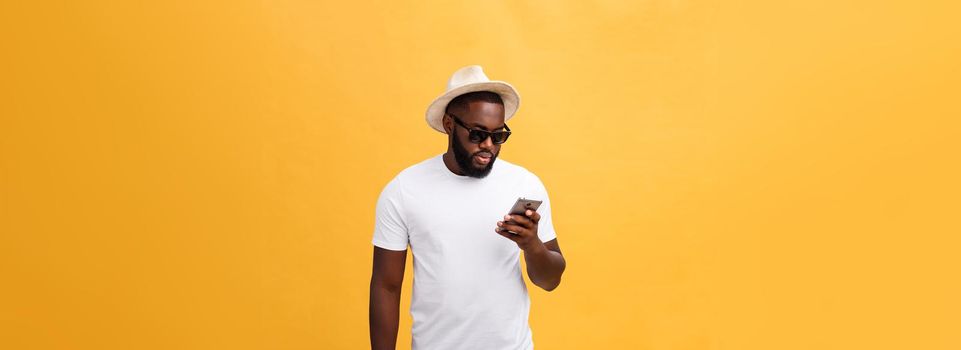 Cheerful African American man in white shirt using mobile phone application. happy dark skinned hipster guy read news from social network in mobile phone