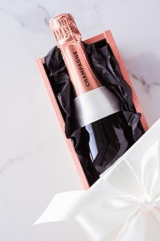 Celebration, drink and branding concept - Champagne bottle and gift box on marble, New Years, Christmas, Valentines Day or wedding holiday present and luxury product packaging for beverage brand